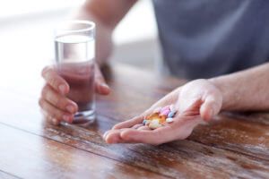 Understanding Acamprosate: Support for Alcohol Recovery Person holding Acamprosate pills and a glass of water for alcohol recovery