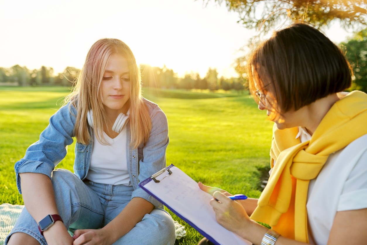 Outdoor Counseling Session for Alcohol Recovery Support Young woman discussing recovery with a counselor outdoors
