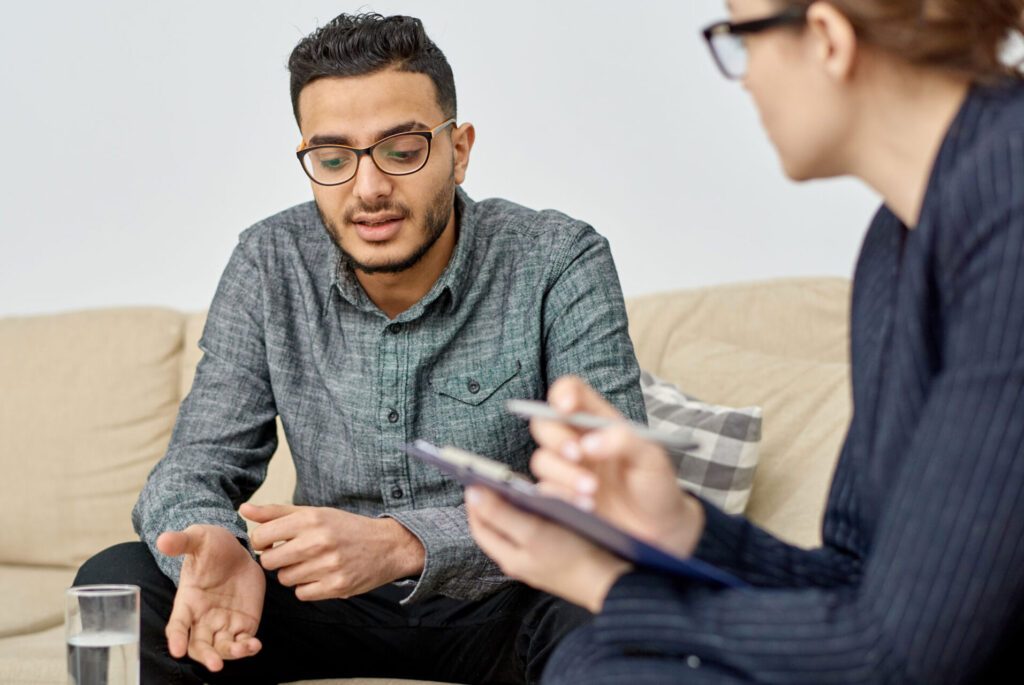Counseling Session for Alcohol Recovery Support Man discussing recovery with therapist on a sofa