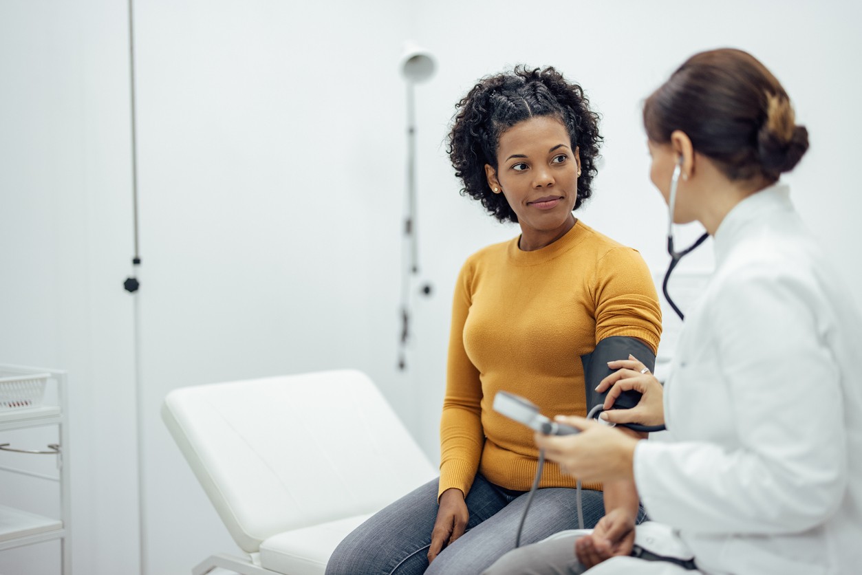 Doctor and Patient Discuss Alcohol Recovery Doctor checks patient's blood pressure during alcohol recovery consultation.