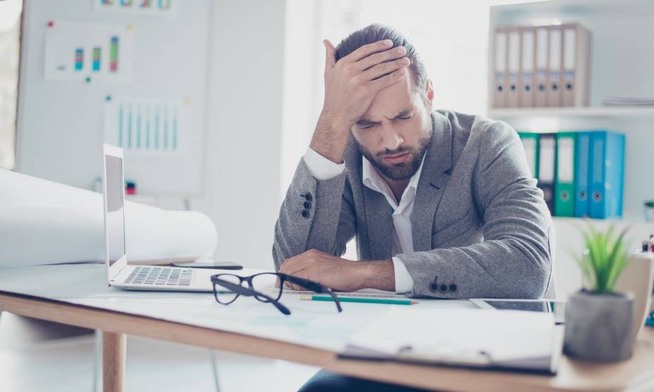 Understanding Comedown Symptoms During Alcohol Recovery Man experiencing comedown symptoms at desk, alcohol recovery context