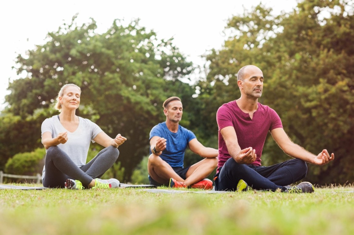 Group meditating outdoors, focusing on covid and mental health recovery