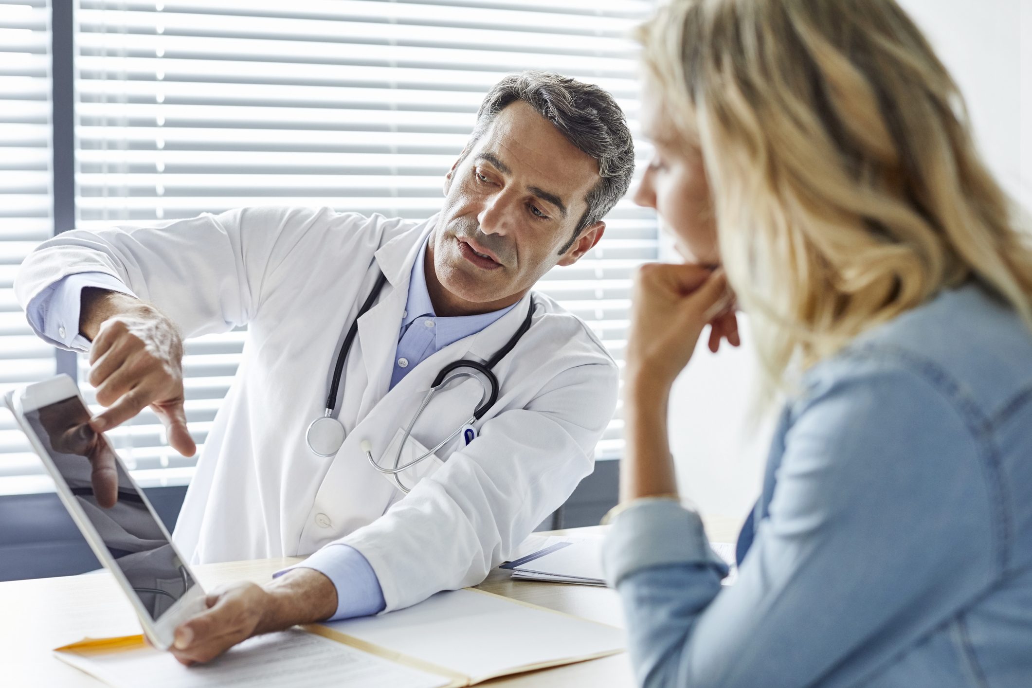 Luxury Rehab Consultation: Doctor Advises Patient Doctor consulting patient about luxury rehab program on tablet