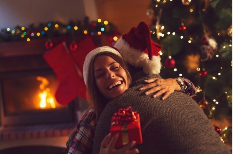 Sober Christmas: Celebrating Joyfully in Recovery People hugging by a Christmas tree, enjoying a sober Christmas celebration.