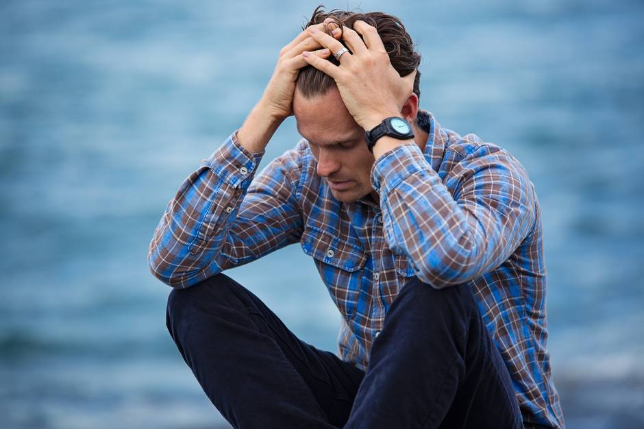 Struggling with Alcohol Addiction? Find Help and Hope Man holding head in hands by water, reflecting on alcohol recovery