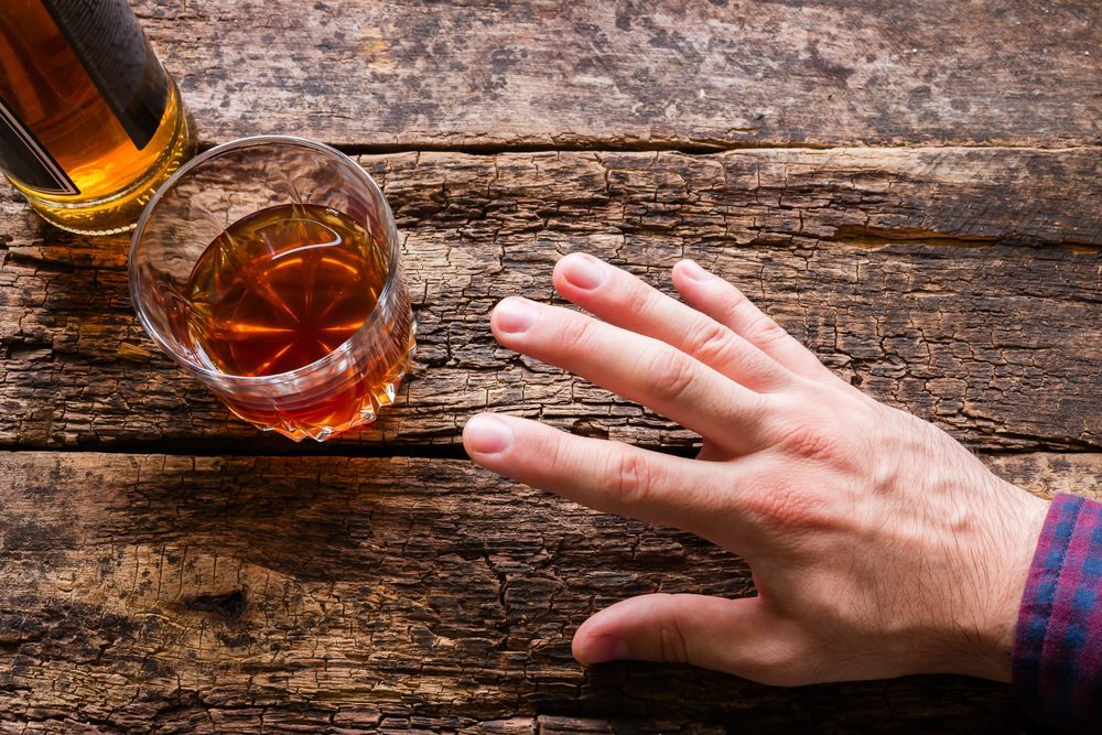 Symptoms of Alcohol Poisoning: Understanding the Risks Hand reaching for a glass of alcohol, showing symptoms of alcohol poisoning risk