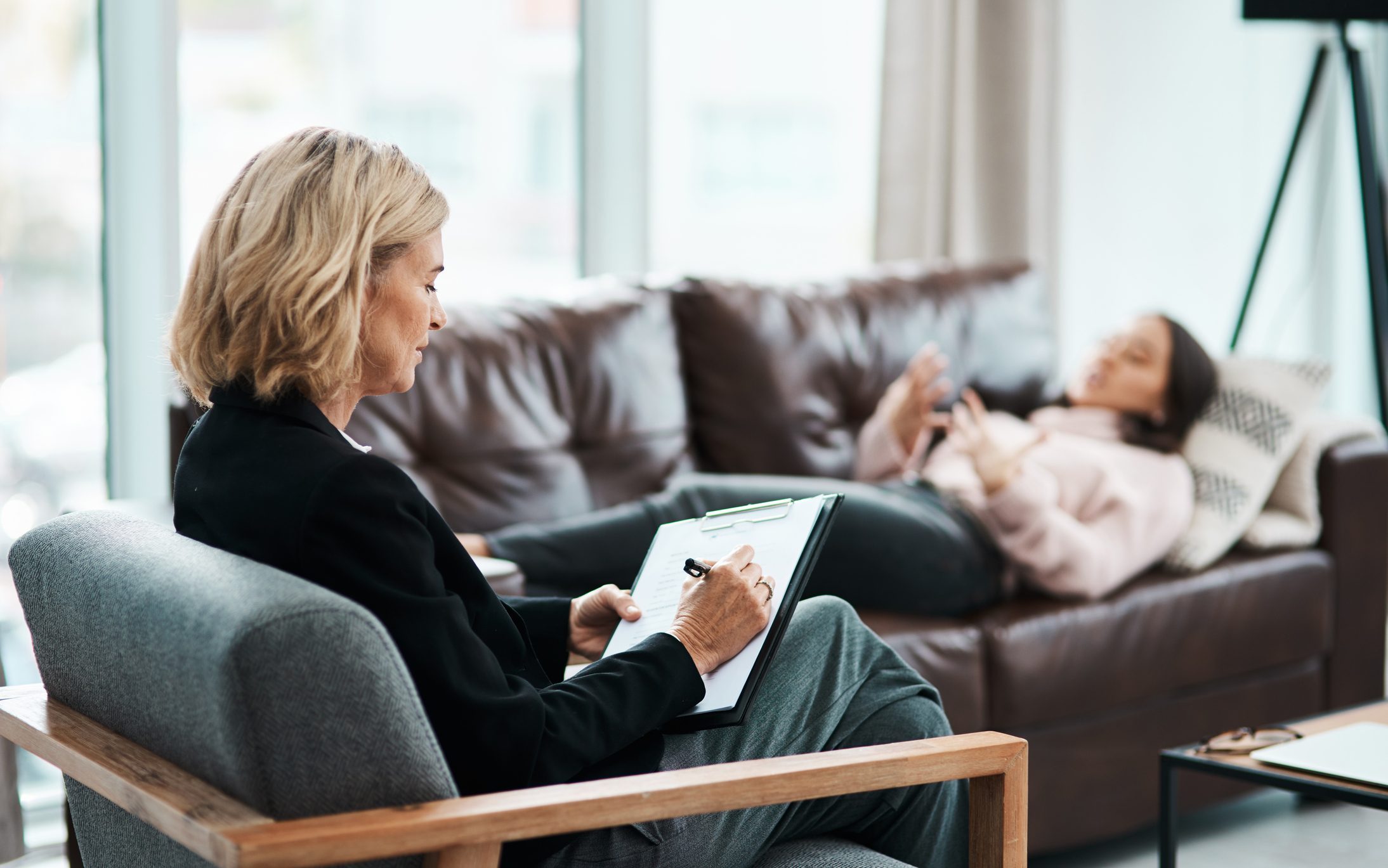 Therapist Supporting Alcohol Recovery Journey Therapist taking notes during a counseling session for alcohol recovery.